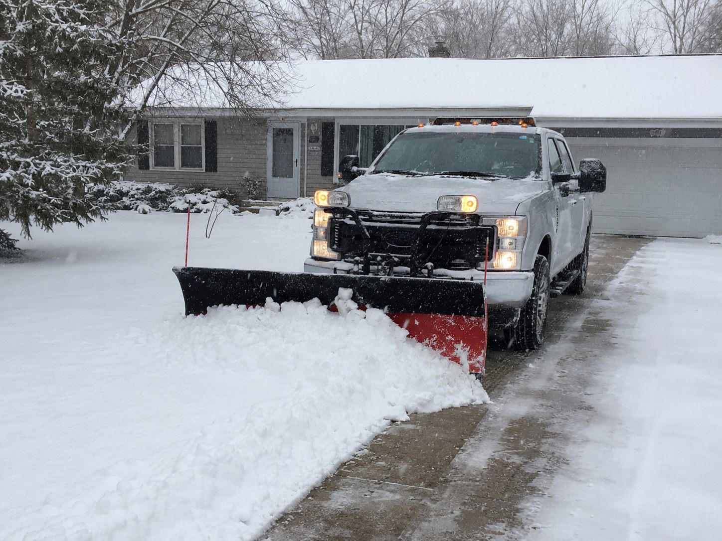 Plow truck clearing a snowy residential driveway